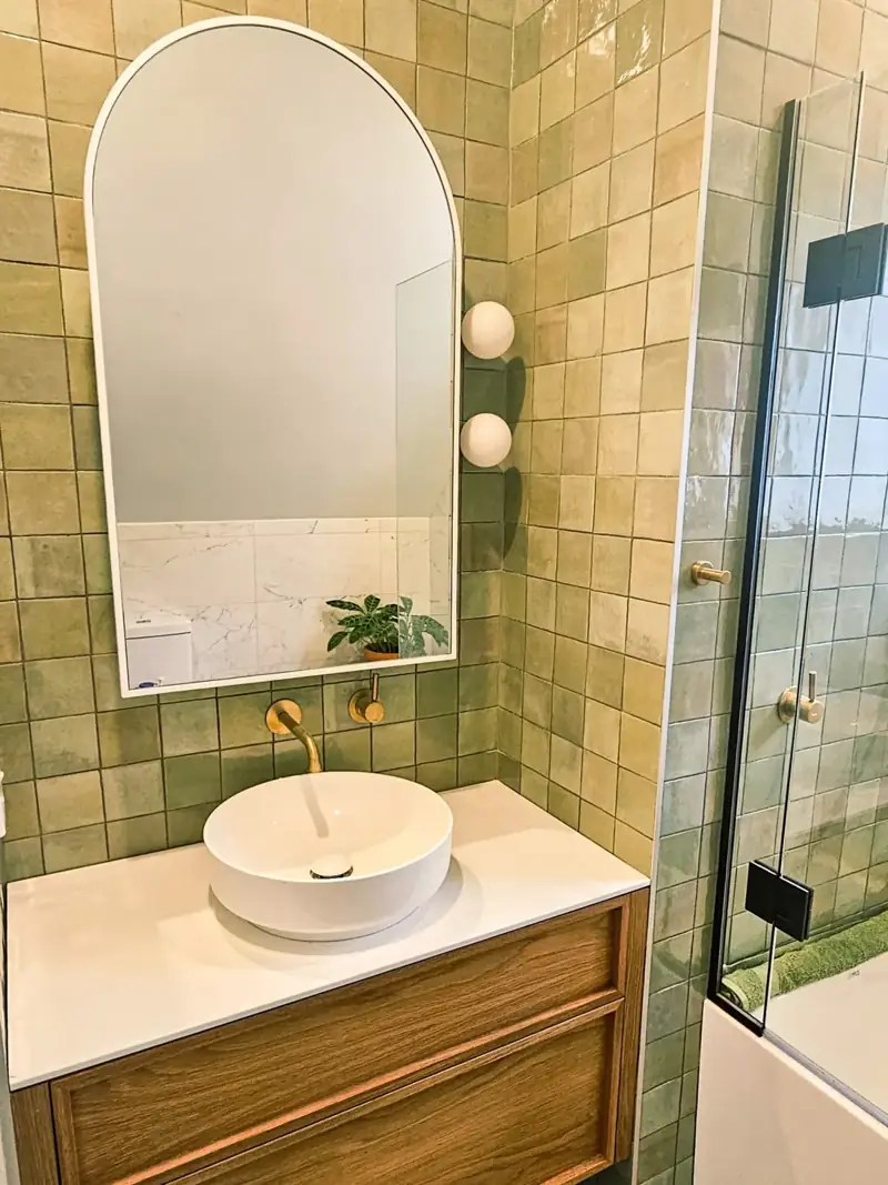 Timber vanity, wall mirror and green bathroom tiles
