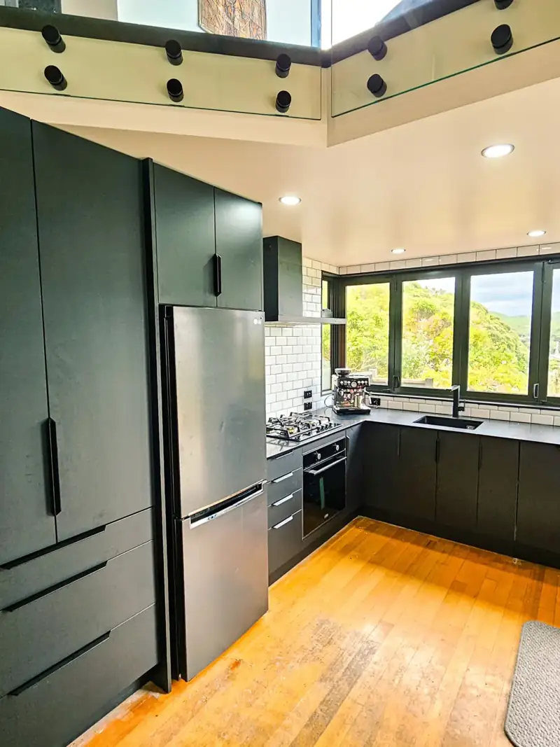 Dark kitchen cabinetry, a stainless steel fridge and timber flooring
