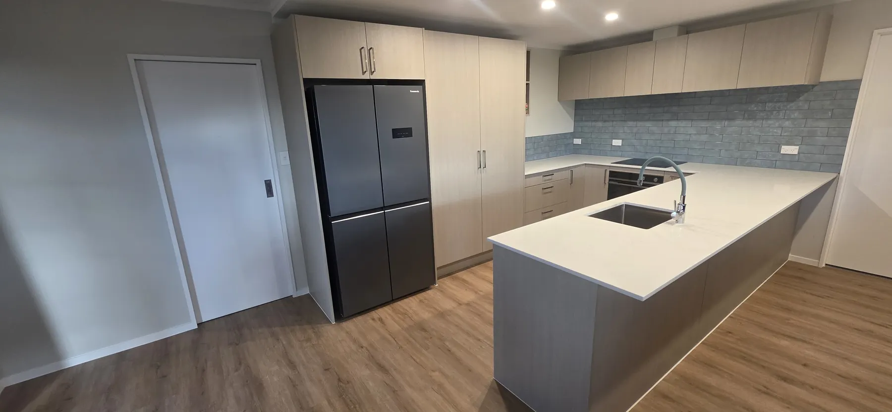 Finished kitchen with stone island and timber flooring